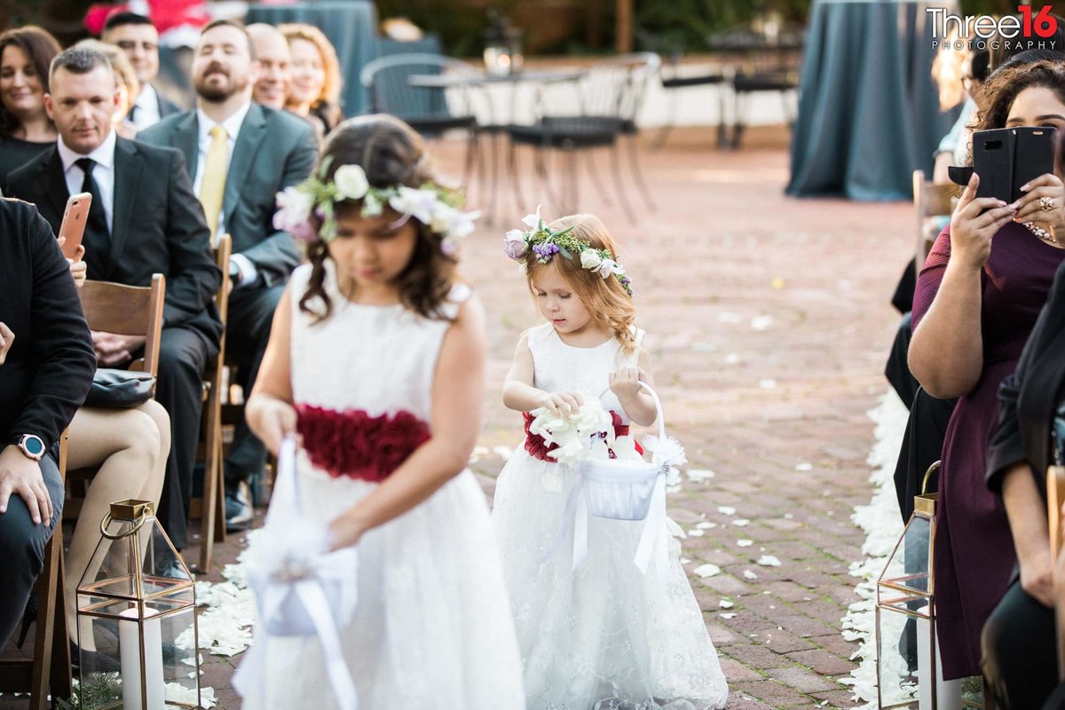 Flower girls drop pedals on the ground as they walk up the aisle