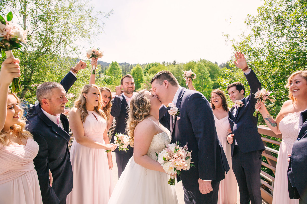 Wedding party cheers for kissing bride and groom