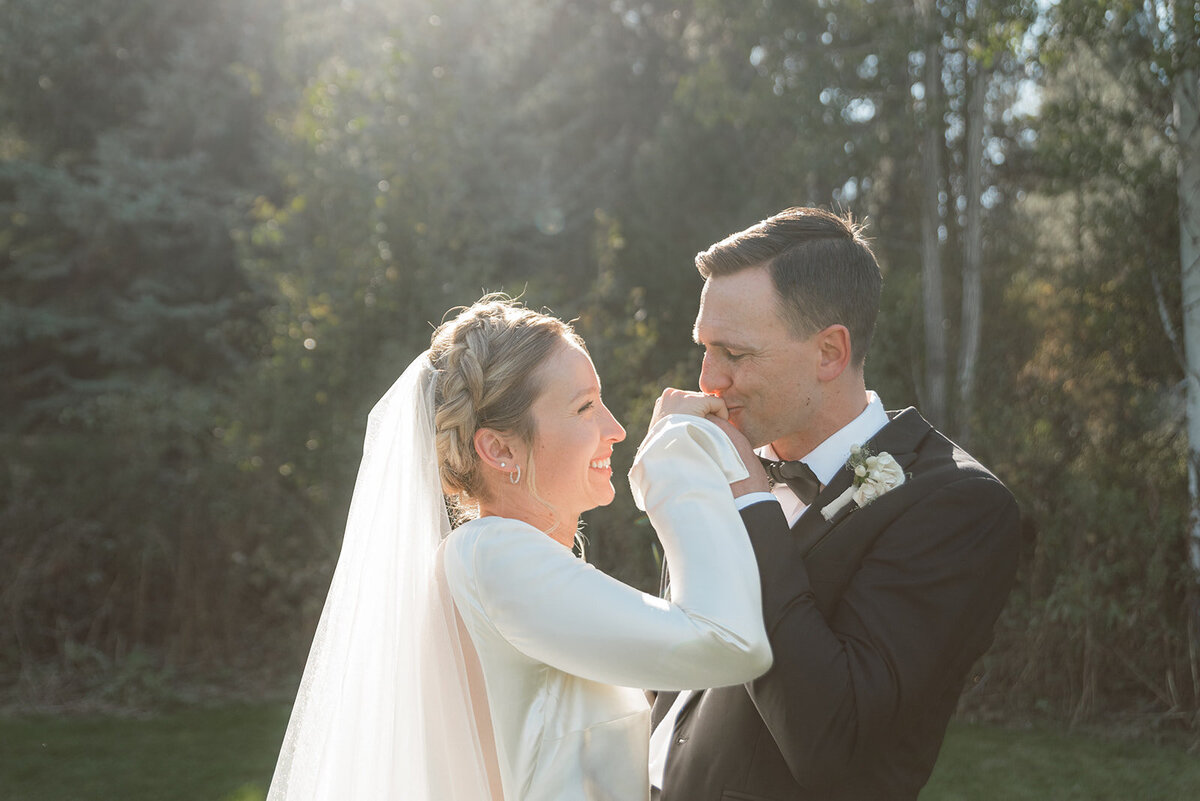 A groom kissing his brides hand.