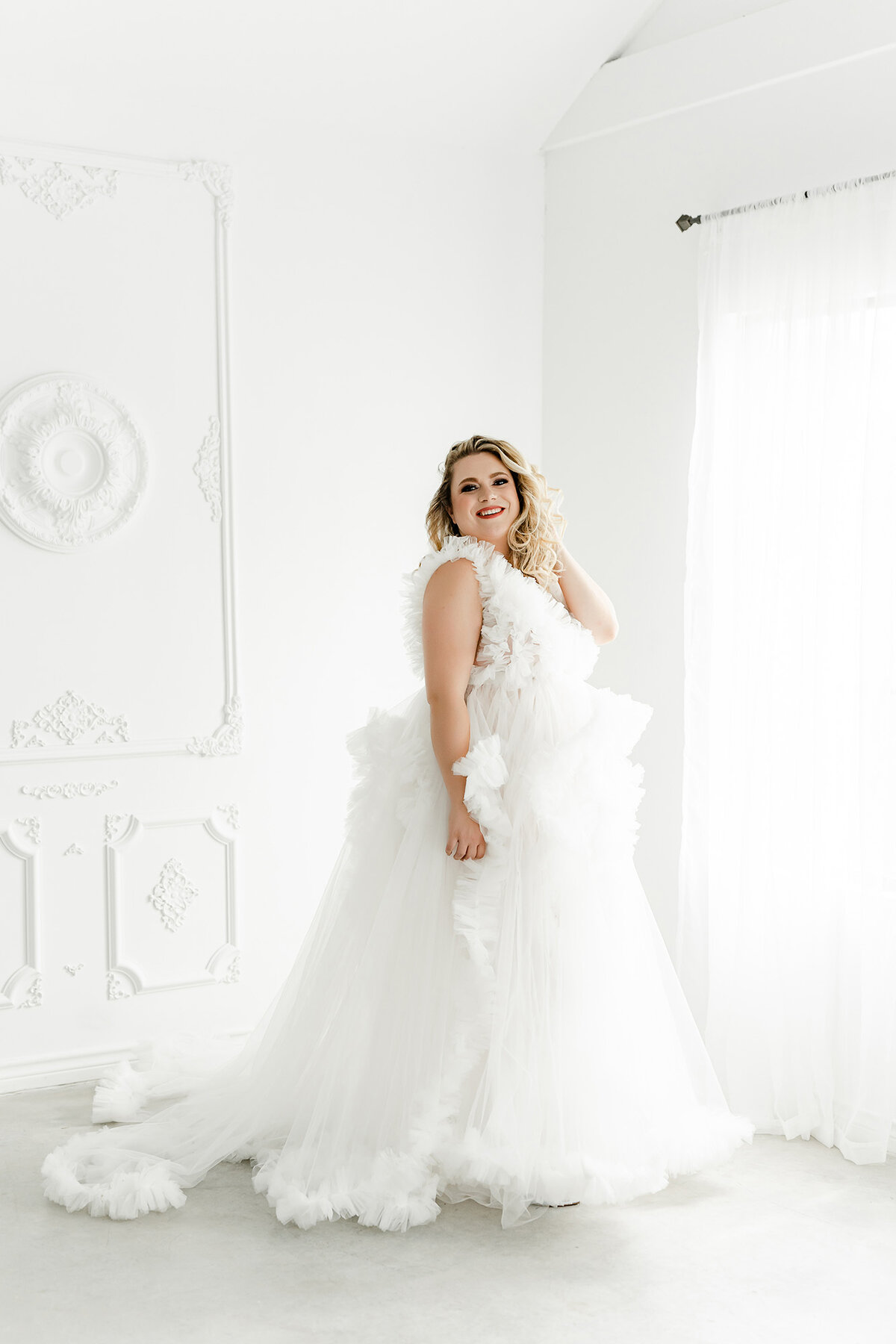 Bright and elegant boudoir photoshoot with woman in flowing wedding style dress