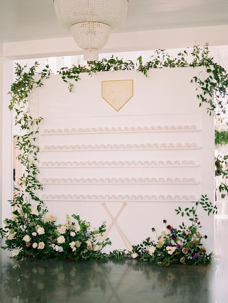 Large white wedding day backdrop decorated with floral arrangements and greenry