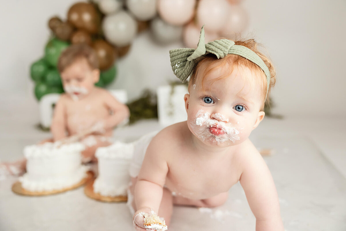 Baby girl with white frosting on her face during her one year cakesmash during her one year session in Minnesota.