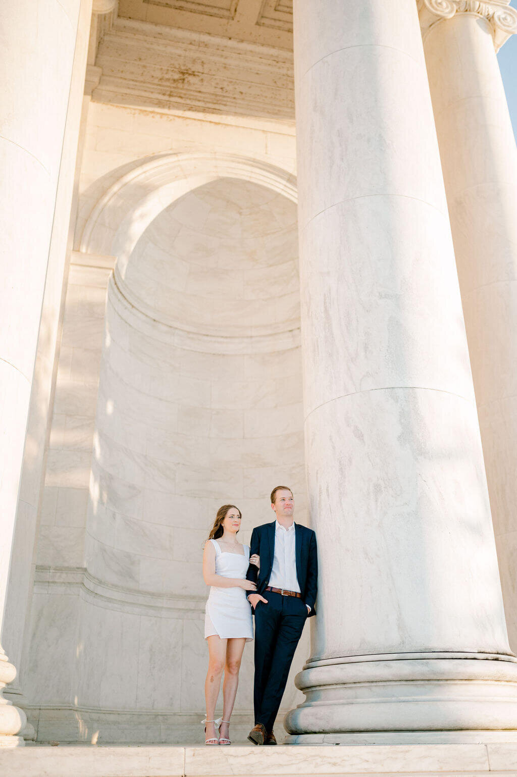 Couple posing for engagement photos, leaning on the columns of the Jefferson Monument.