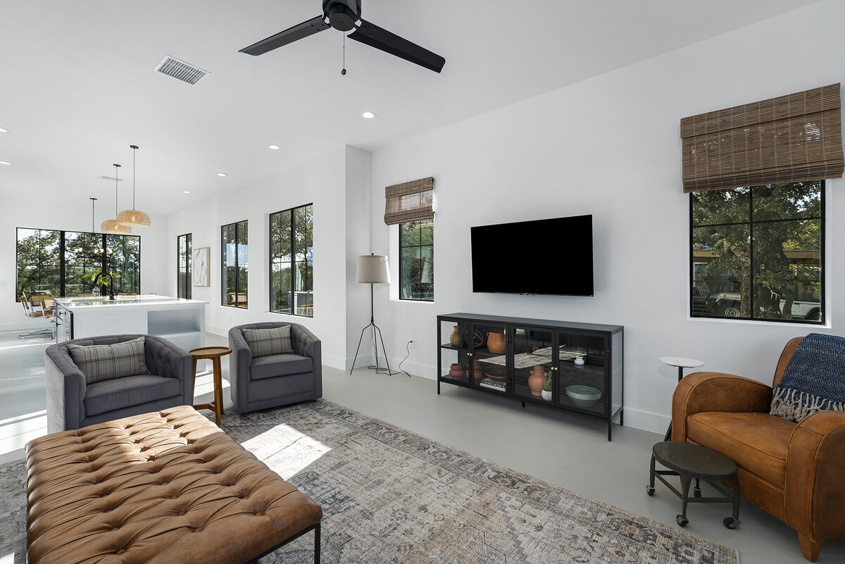 living room with white walls, black windows and bamboo shades