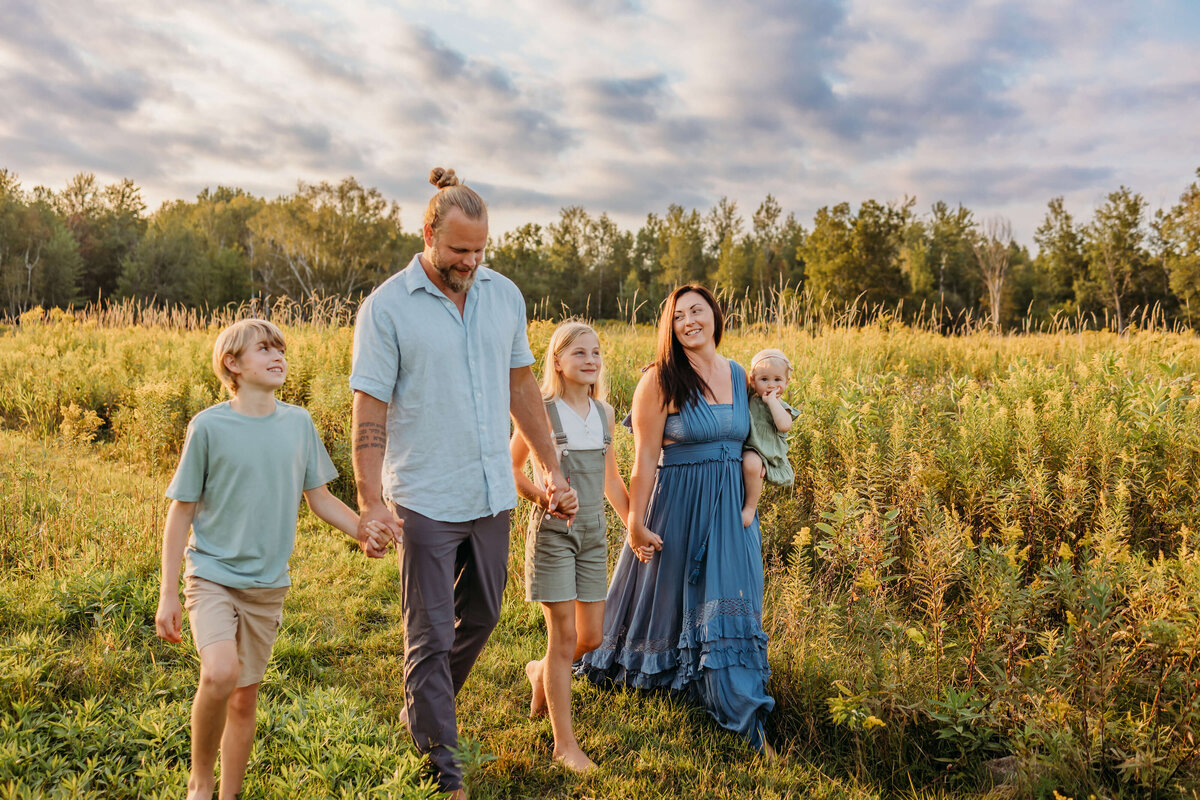 Eau Claire family photo in field at sunset walking and smiling