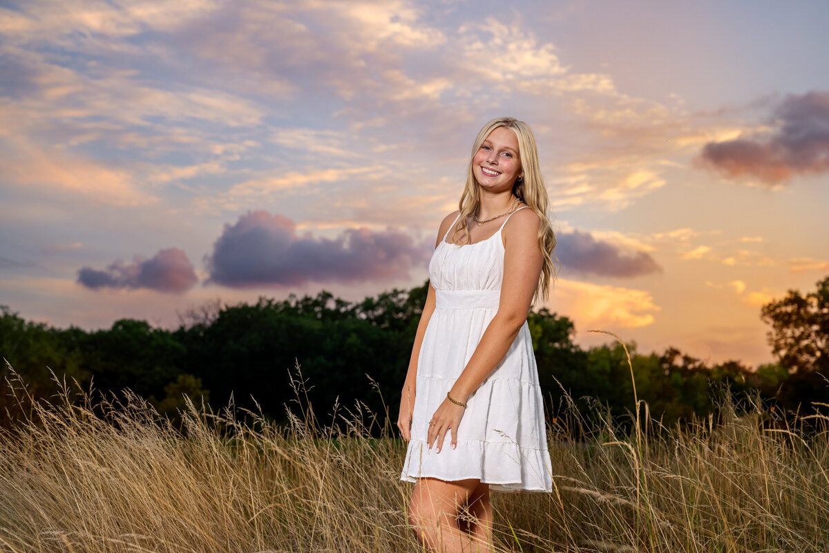 New Brighton Minnesota high school senior picture of girl wearing white dress in long grass at sunsert