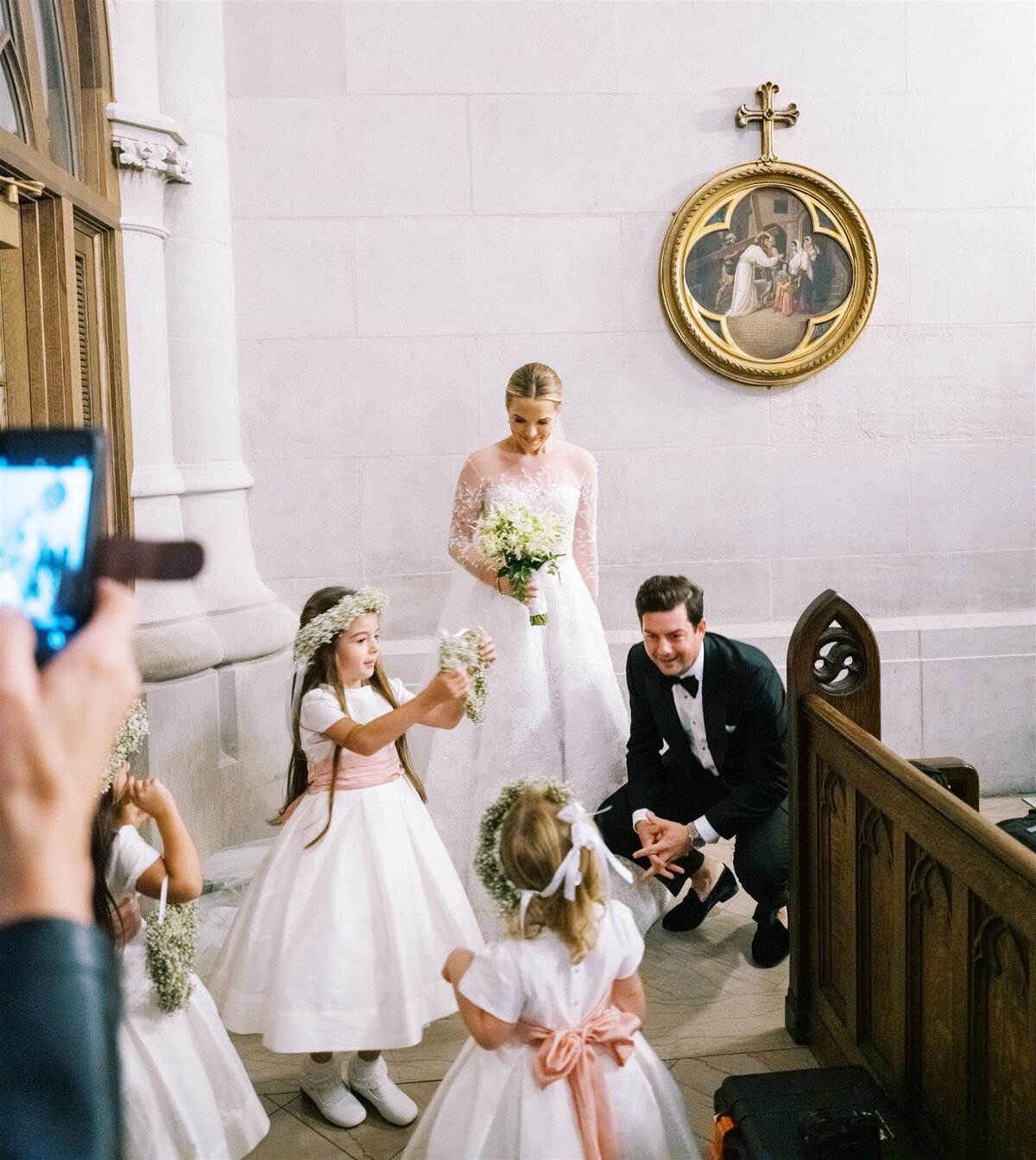 A picture of the bride and groom talking to the flower girls. 