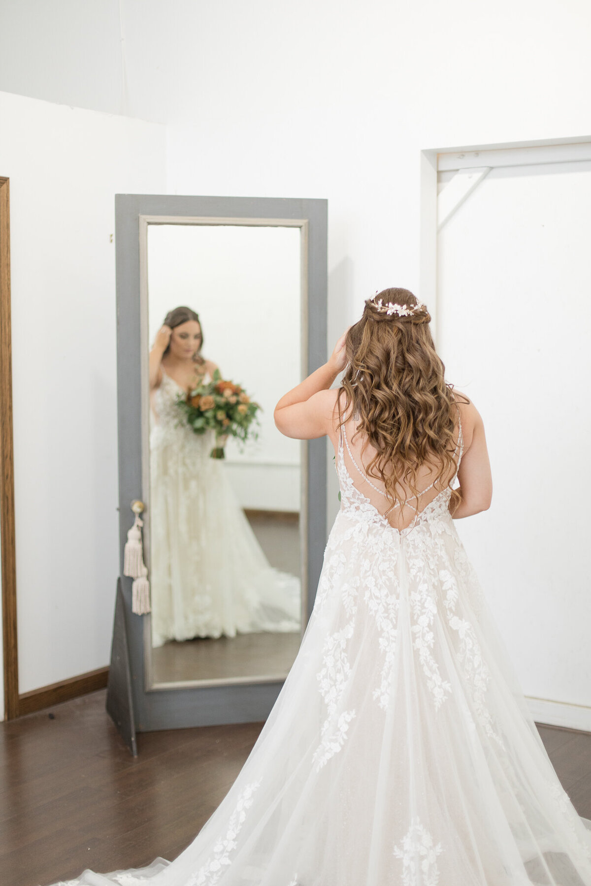 young woman looks in the mirror before walking up the aisle at her wedding in the lake erie building in cleveland, ohio.