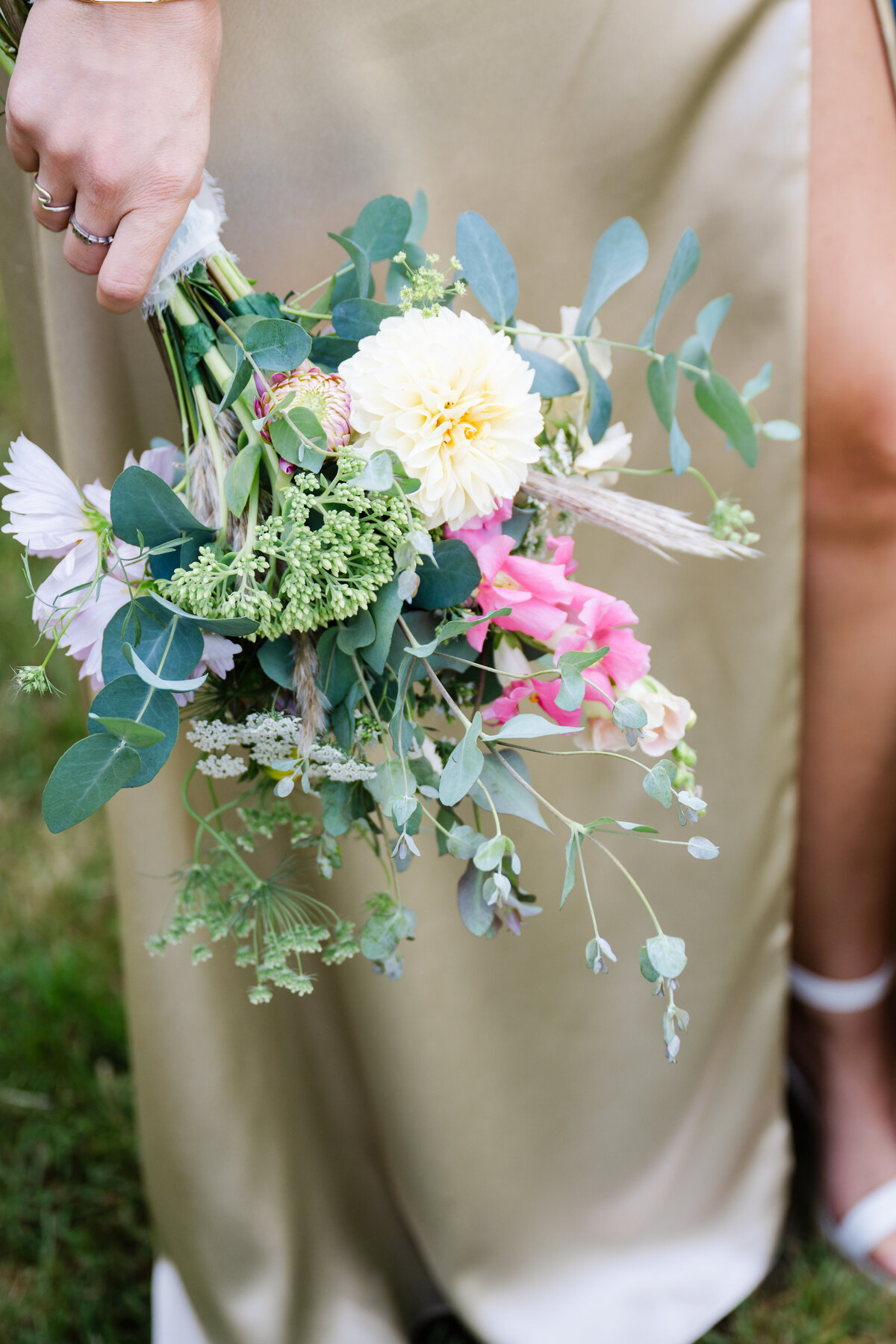 close detail photo of bridesmaid in gold dress holding pastel bouquet