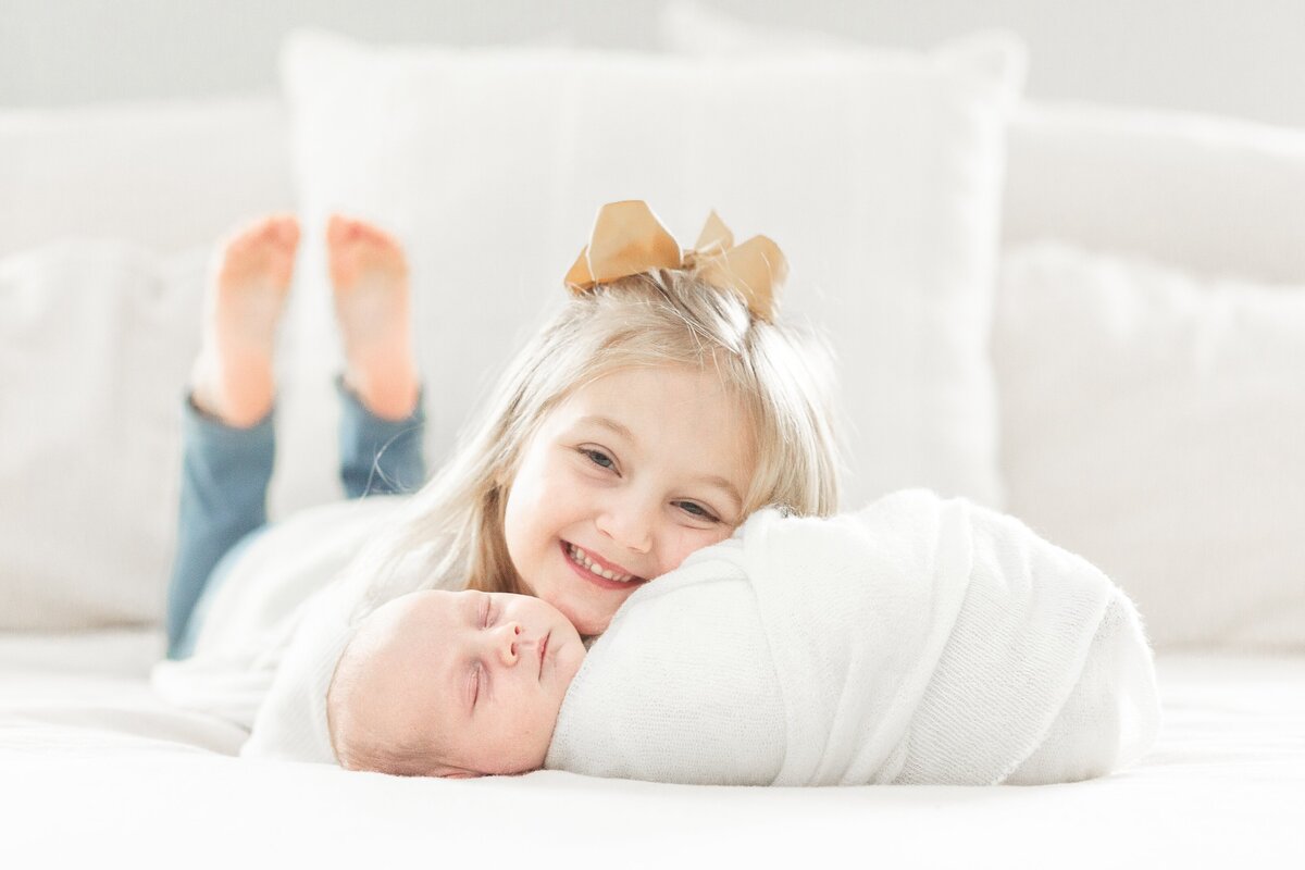 Big sister smiles with baby brother during in home newborn session taken by Brooke Leigh Photogrpaher in Wixom, Michigan