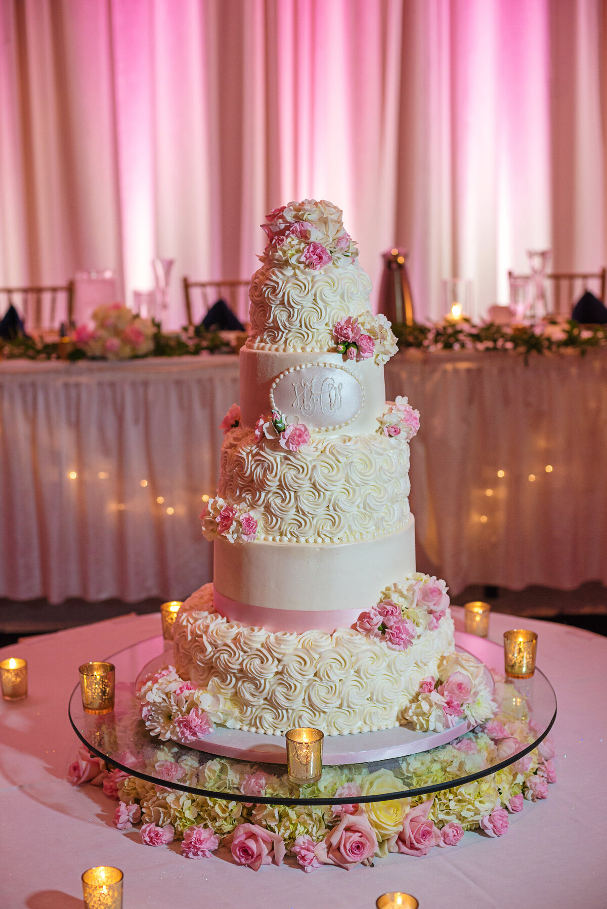 Wedding cake with pink flowers and white frosting.