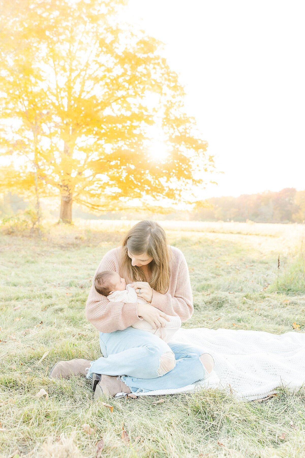 mom holds baby during outdoor newborn photo session with Sara Sniderman Photography