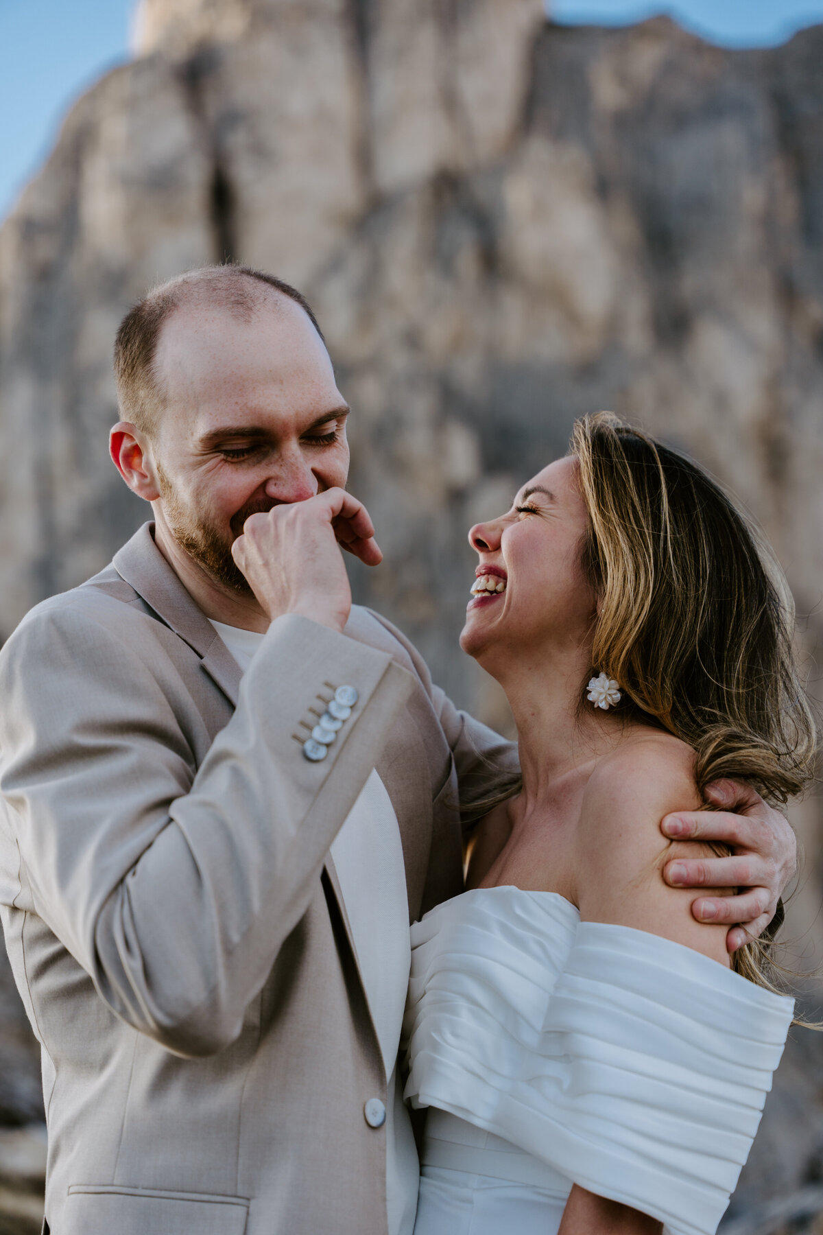 Bride and groom laughing together during candid mountain moment
