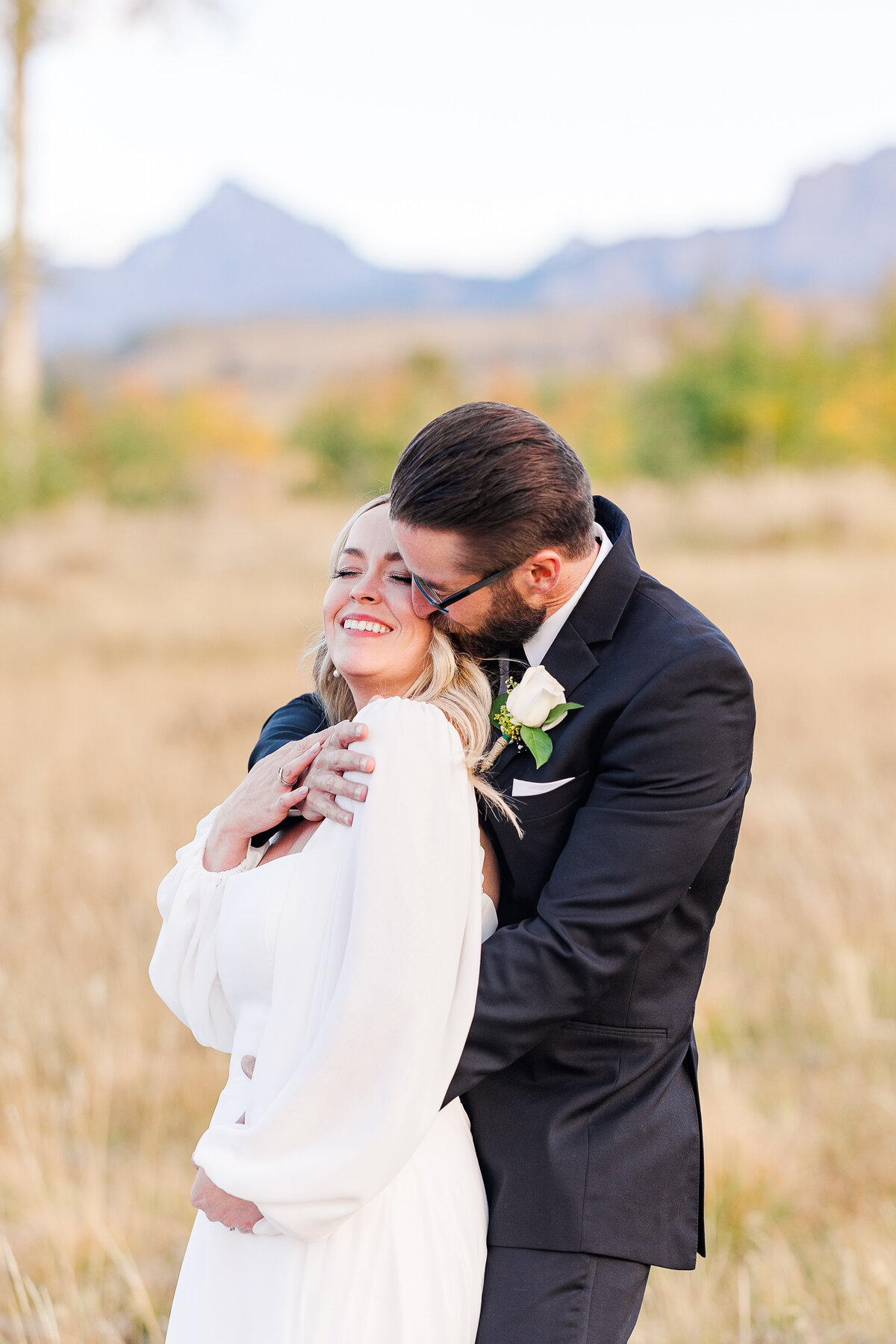 Bride and groom smiling as the groom hugs the bride during their Dallas Divide wedding in Colorado, capturing an intimate moment of joy