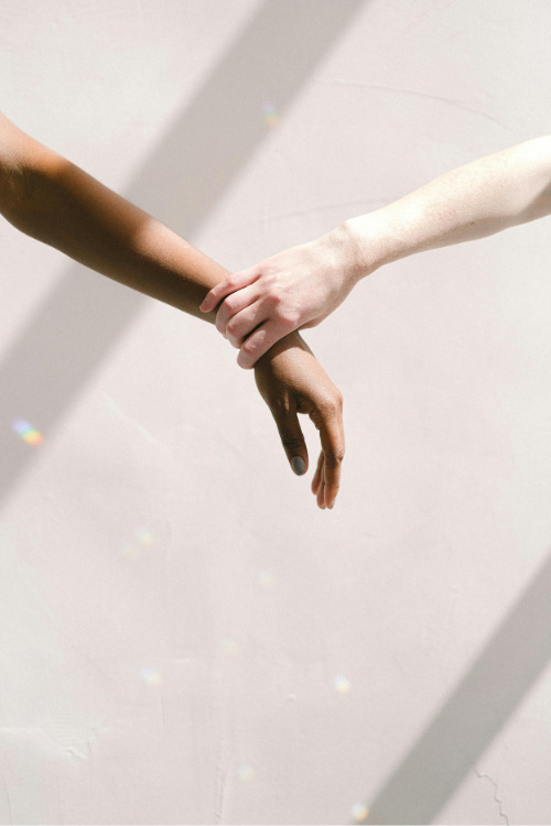 a light skinned hand taking hold of a dark skinned wrist