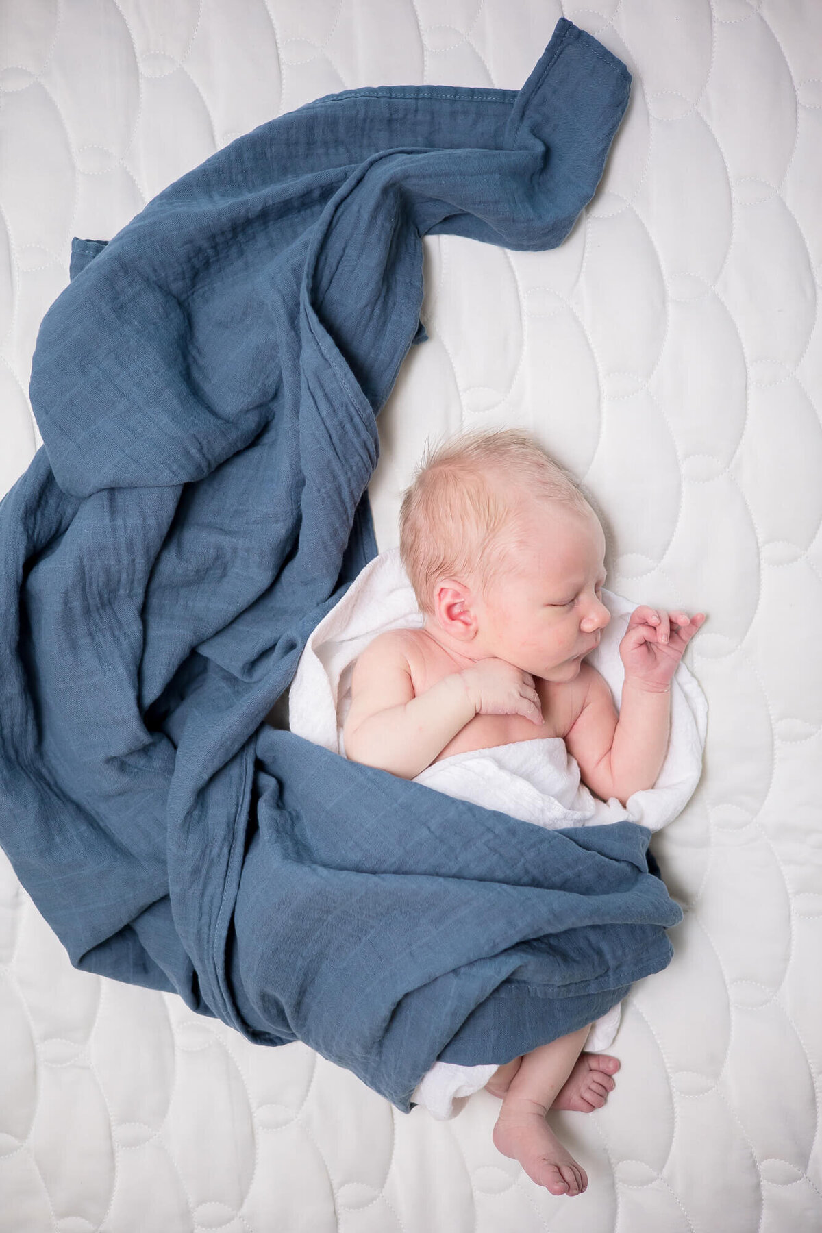 view from above of newborn baby boy wrapped and surrounded by dusty blue swaddle