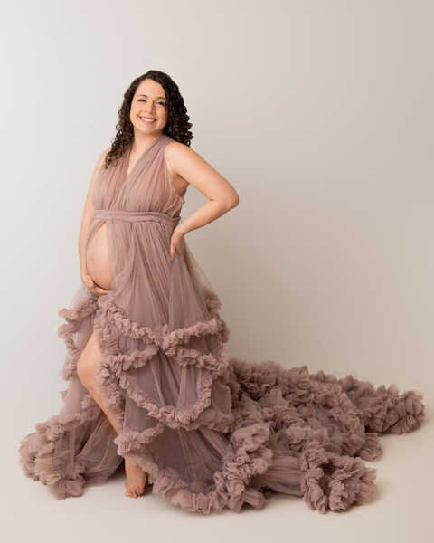 Pregnant mother in flowing mauve gown posing for Houston maternity photography.