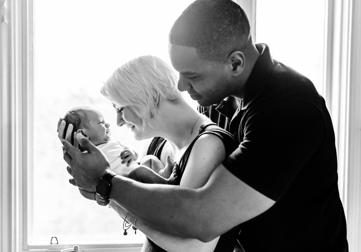 newborn-in-parents-arms-black-and-white-in-home-session