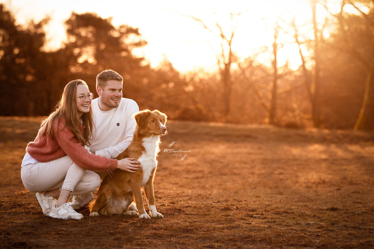 En koppel zittend met hun hond tijdens een zonsopgang fotoshoot in Nijlen. 