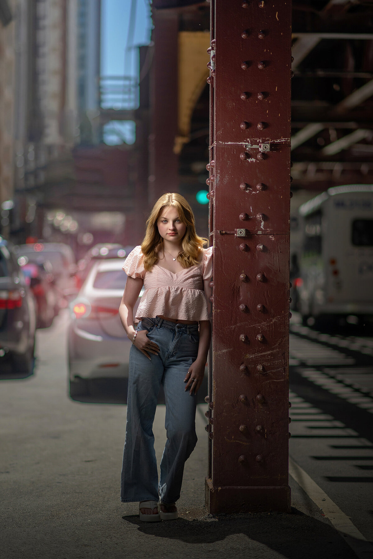 A high school senior leans against an iron beam on the street for her Iowa Senior Photographer