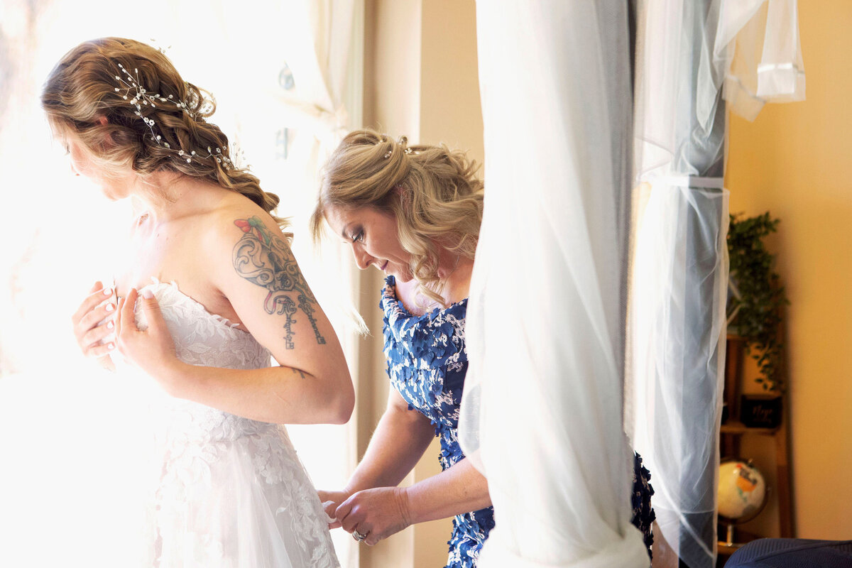A mother helps her daughter get into her wedding dress,
