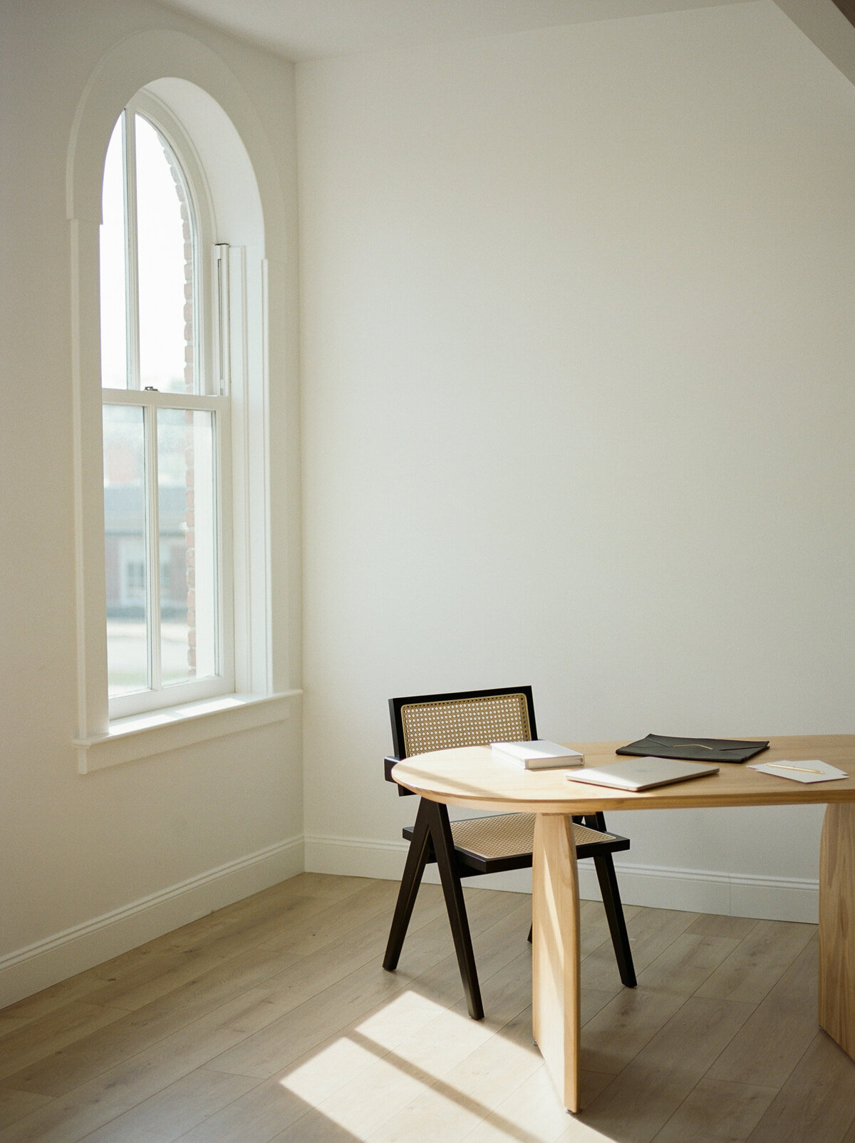 clean, natural light photography studio with wood desk, chair, arched windows captured by film branding photographer Christina Harrison