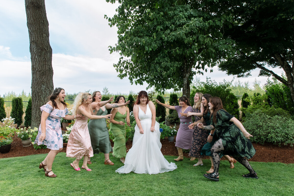 Bridesmaids rush towards bride as she laughs on her wedding day