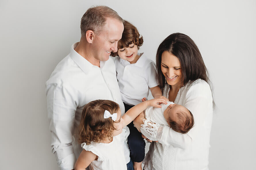 Family looks at and touches their newborn baby.