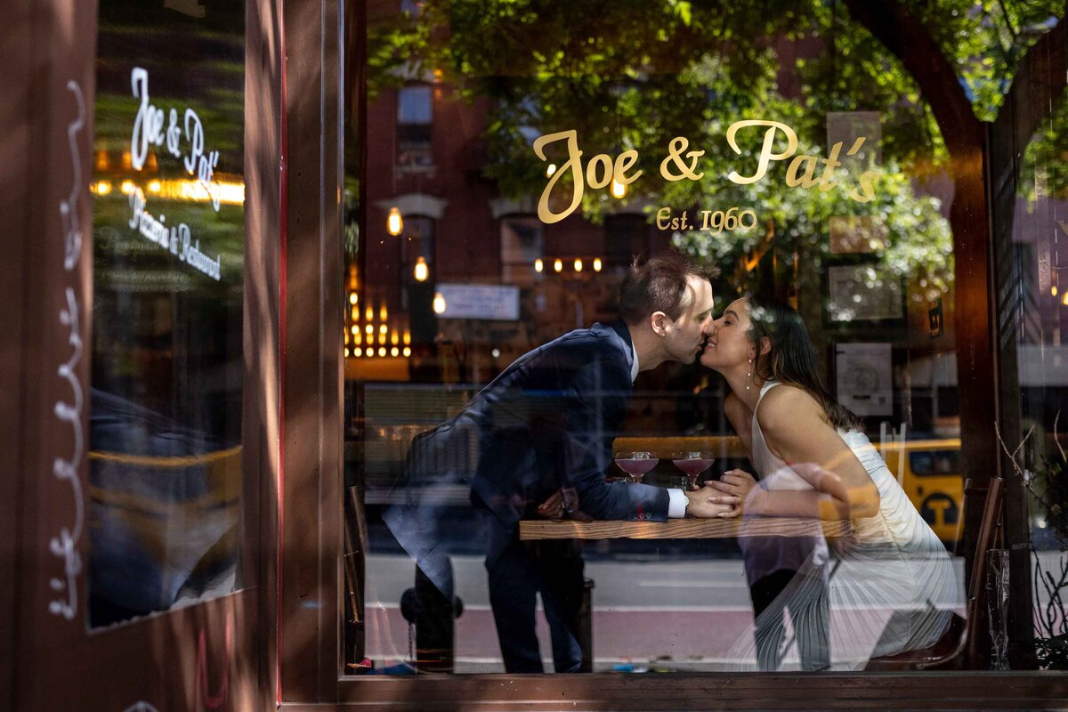 A couple leaning over a table and kissing.