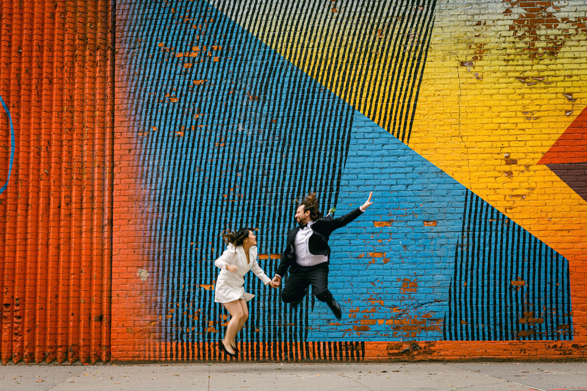 A couple jump in front of the  BQE DUMBO Mural