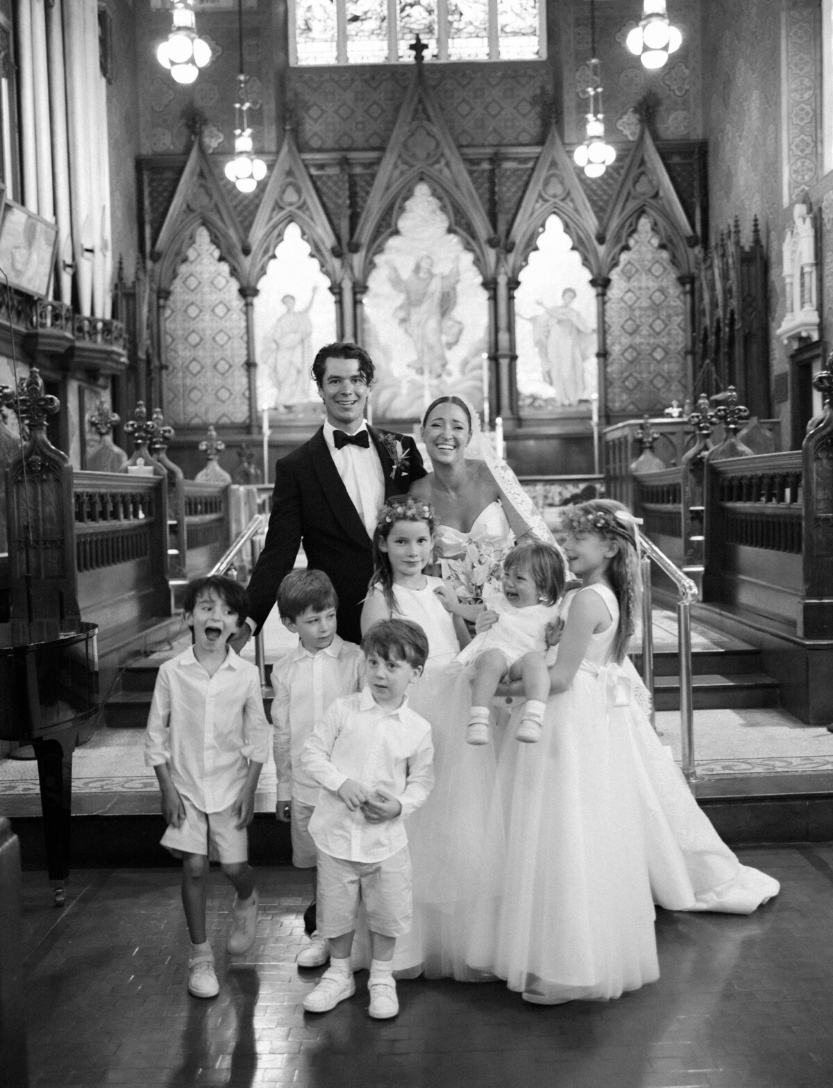 a natural wedding photo of a couple laughing with family and kids 