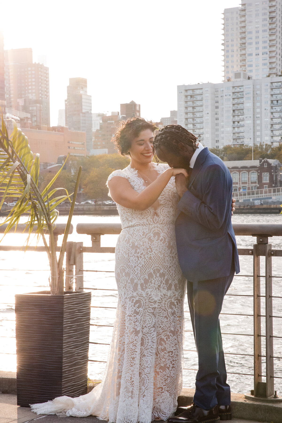 Groom kissing his bride's hand during sunset light in Roosevel Island's The Sancturary's dock.