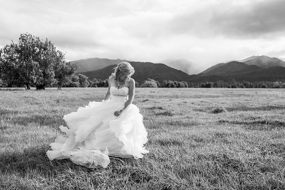 Bride twirling wedding dress in a field with cloudy skies