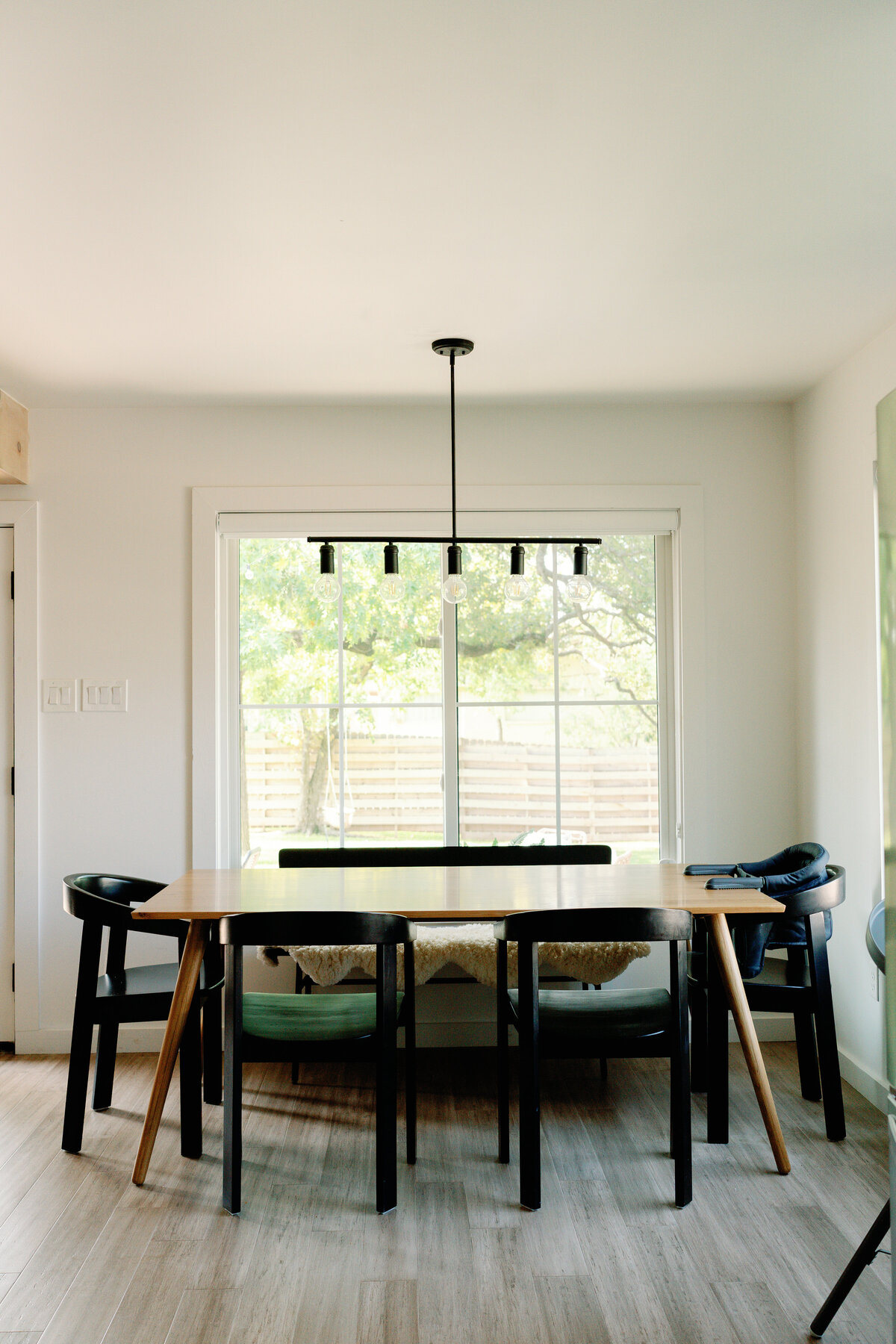 wood dining table with modern black chairs and black pendant light