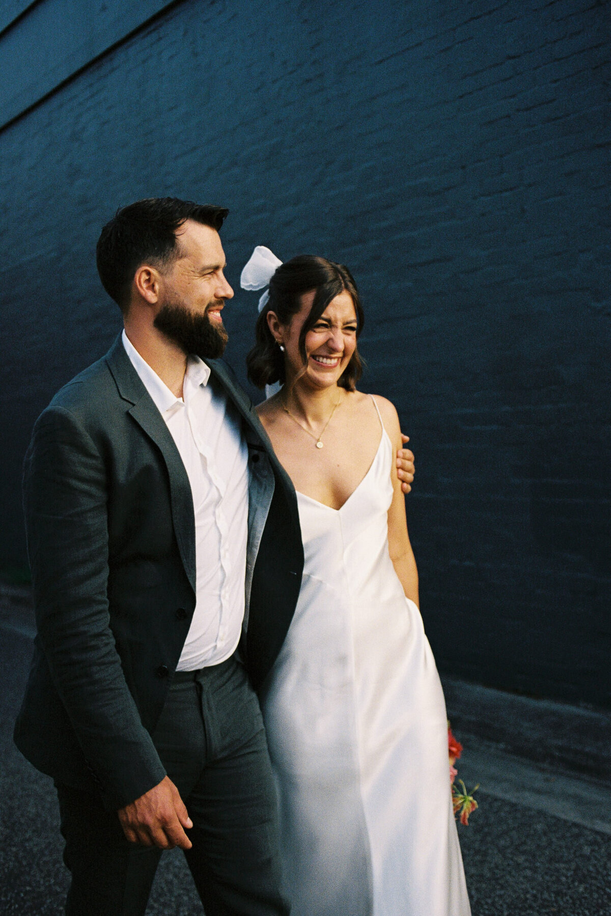 Couple laughing in a laneway during wedding portraits at Glasshaus Inside, captured on 35mm film by Melbourne wedding photographer