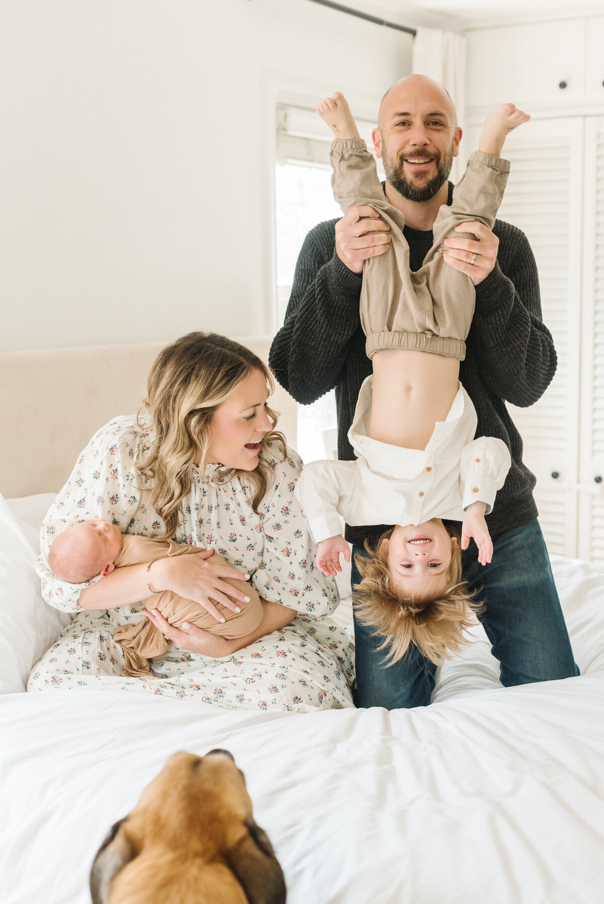 Dad holding child upside down while mom looks on holding newborn - Washington DC Newborn Photographer