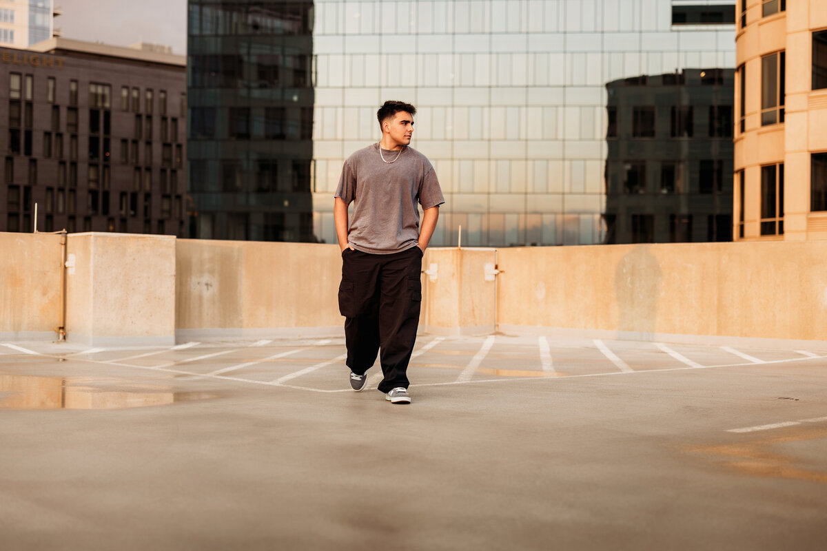 High School senior boys walks on the roof of a high rise building in Denver for an urban background for his senior portrait session