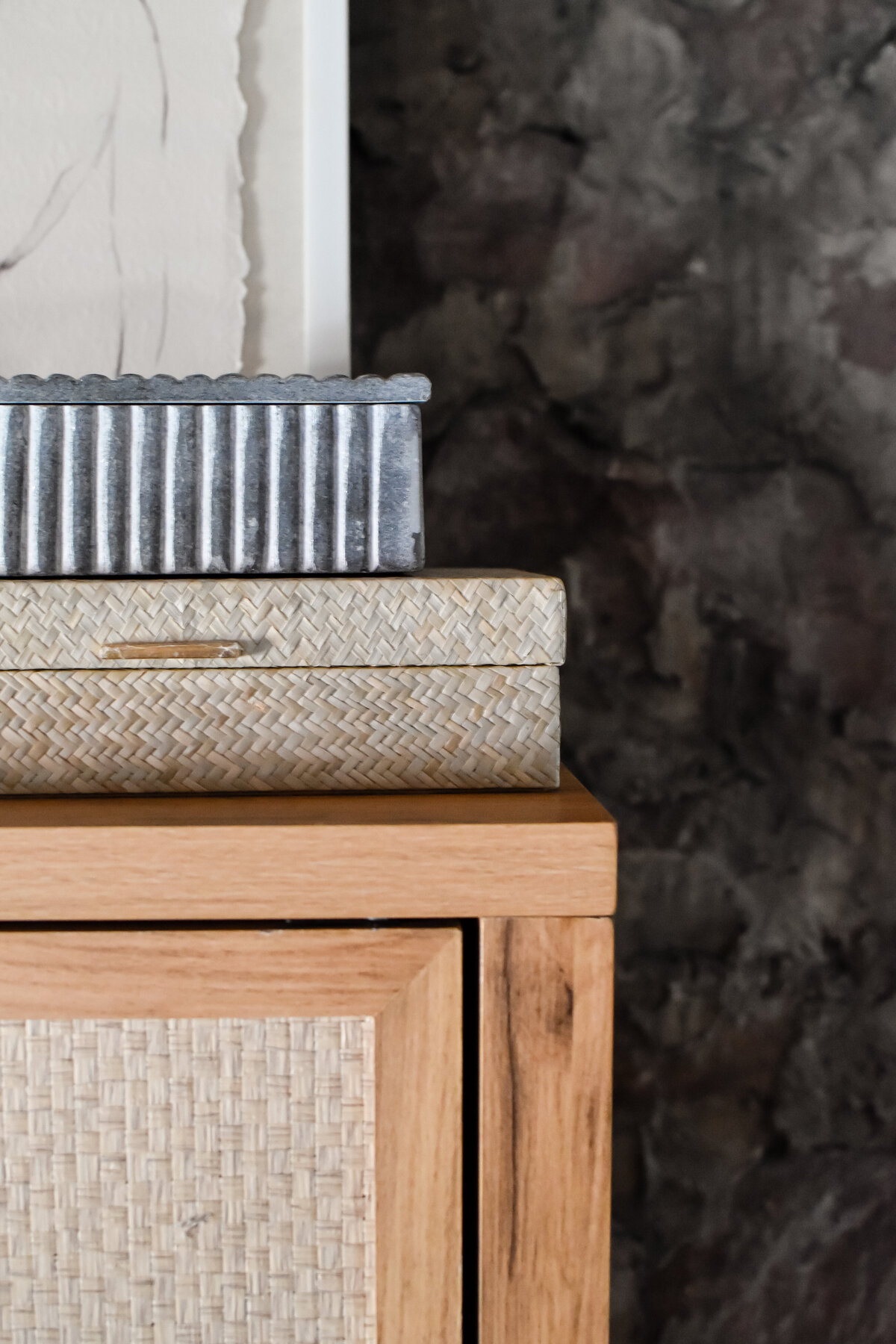 Stacked decorative boxes sit on a boho console table