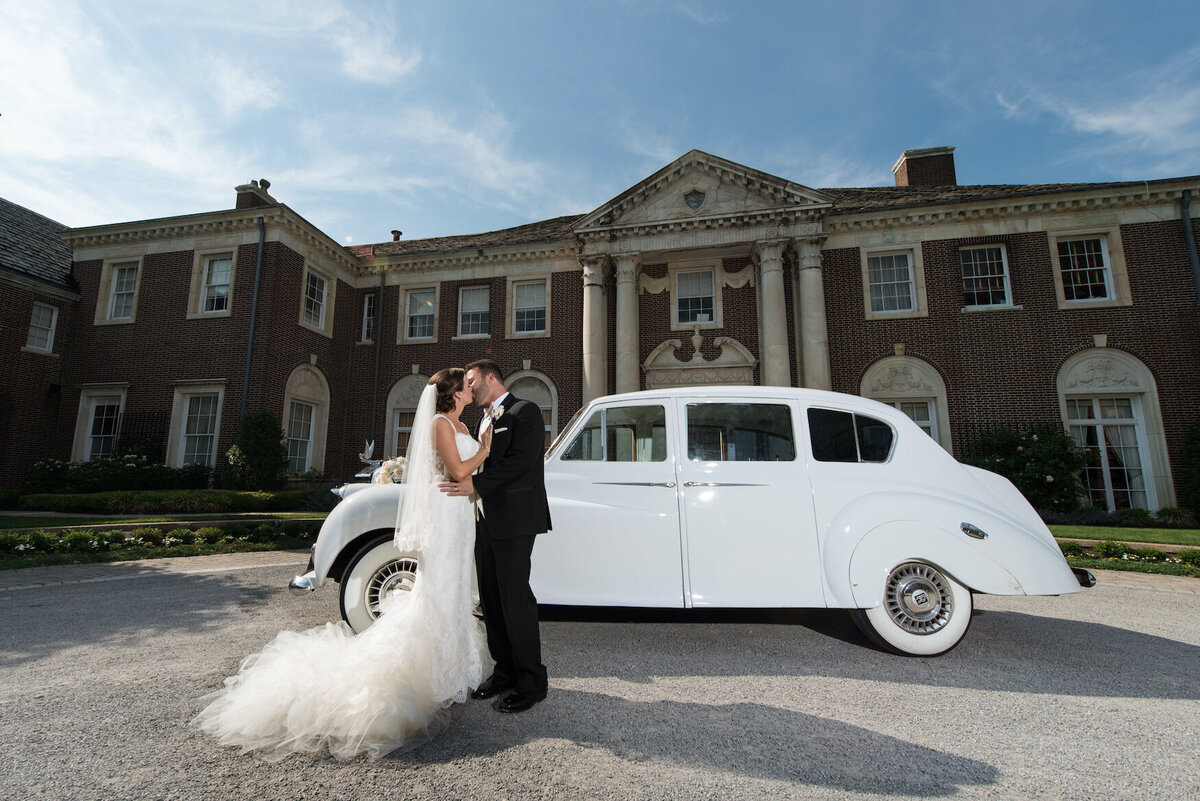 bride and groom kissing by the car at de Seversky Mansion