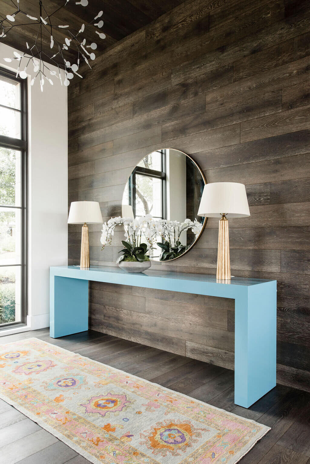 blue side table and orange rug against a wooden wall