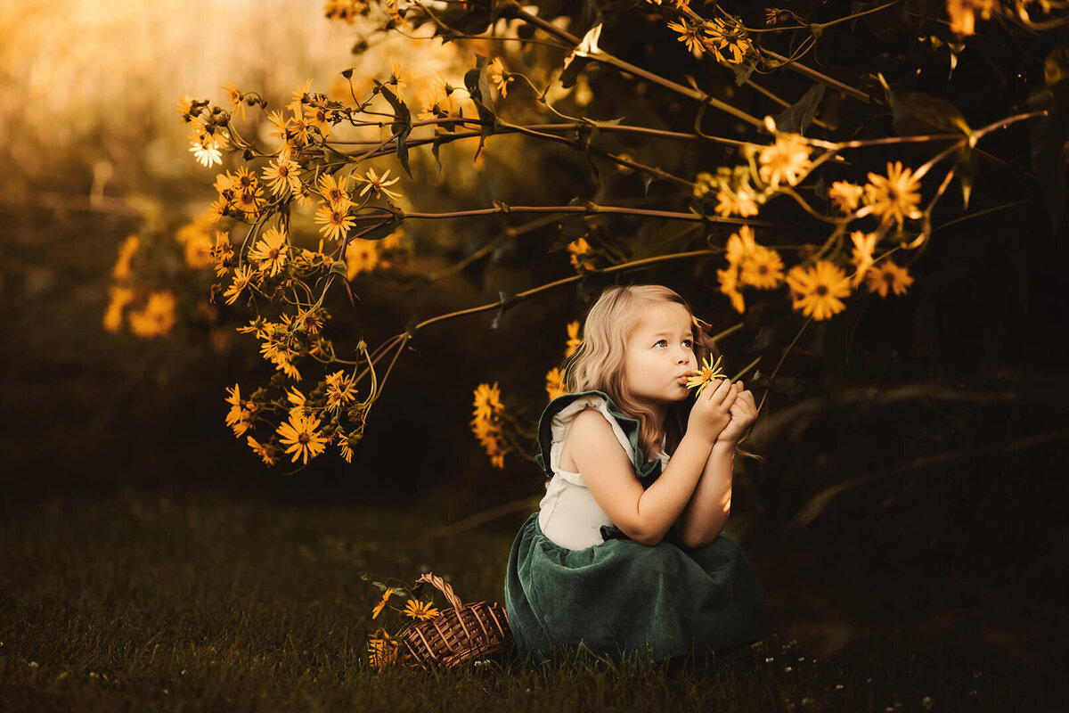 little girl in a squat smelling flowers