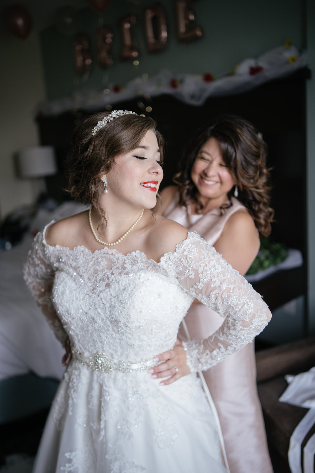 Bride smiles at her mom while bustling her gown as she gets ready for wedding ceremony at The Spire downtown San Antonio