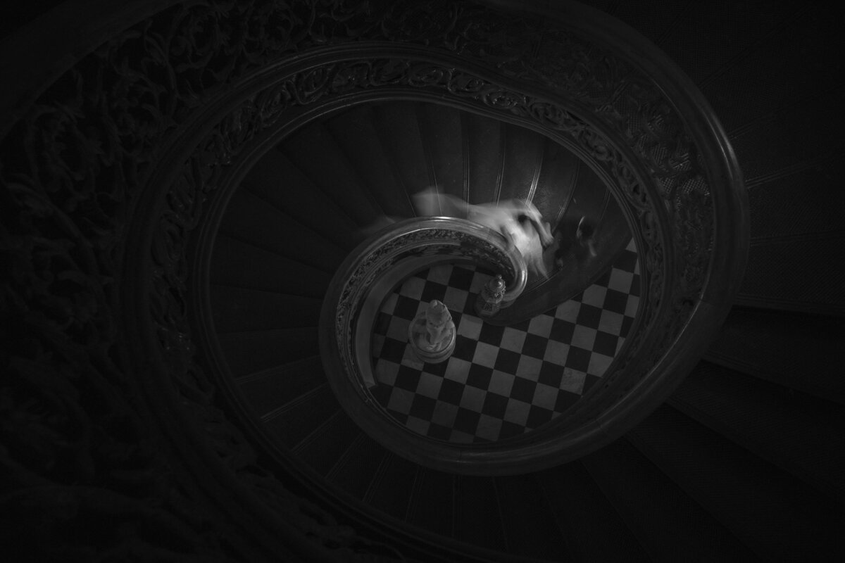 View looking down a spiral staircase as a bride walks down it.