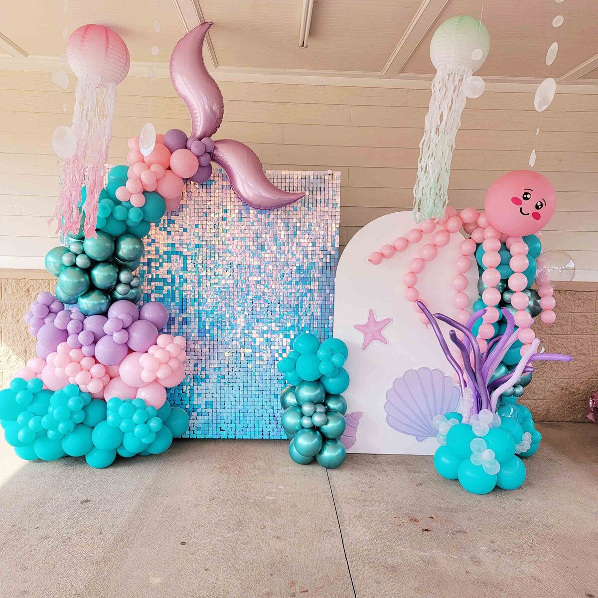 The enchanting underwater realm with air with flair decor backdrop and decor rentals, featuring the whimsical magic of a little mermaid girl party setup.