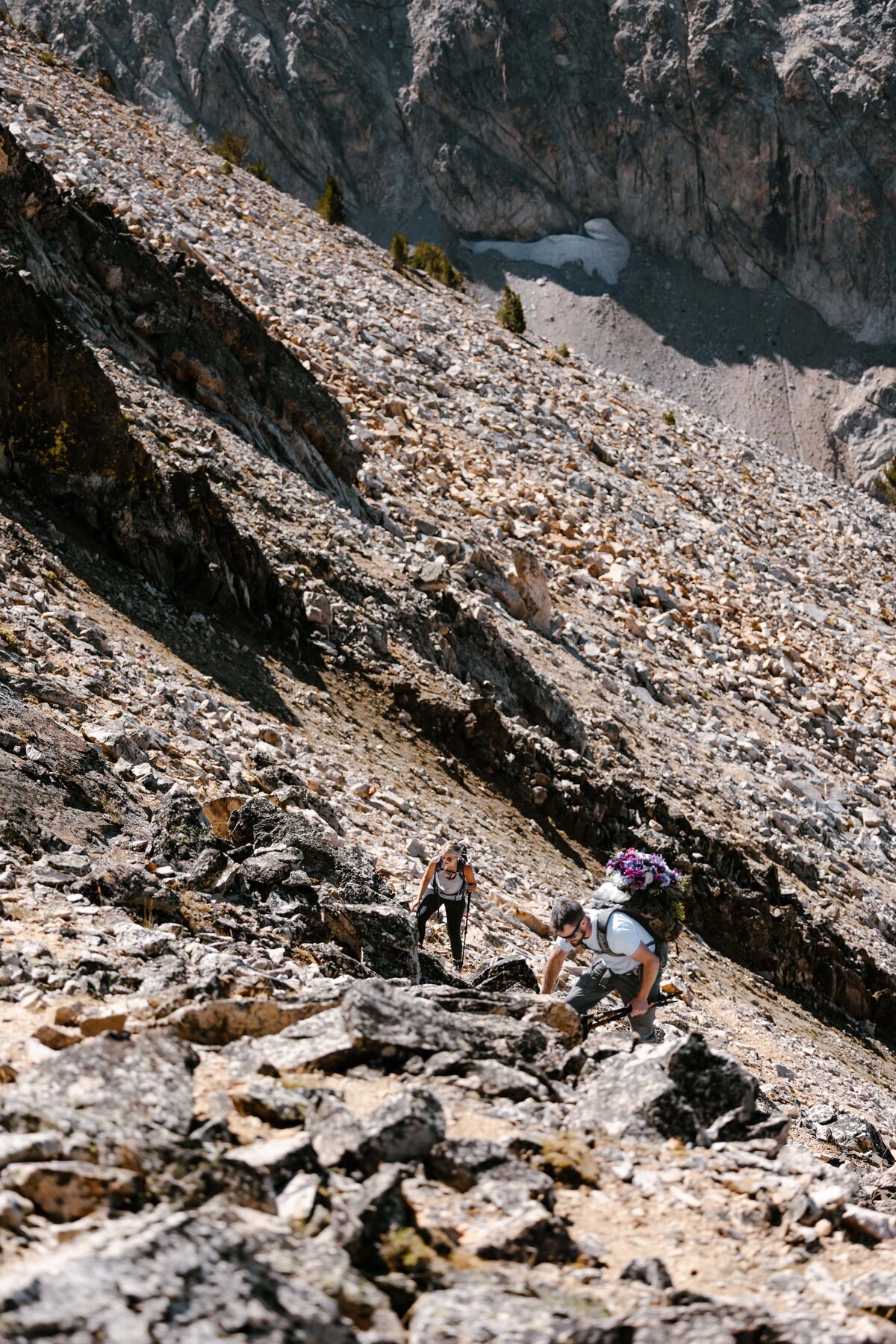 A couple climbing to the top of a mountain peak in Idaho for their elopement ceremony