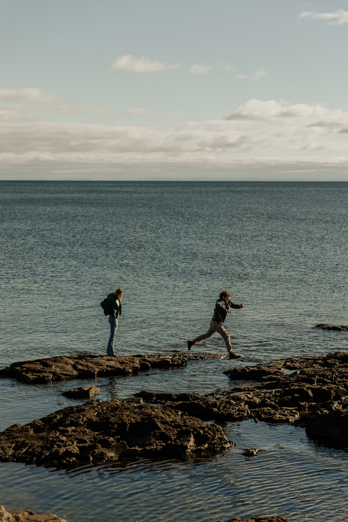 Couple Running and Jumping rocks on the Minnesota North Shore on Lake Superior 