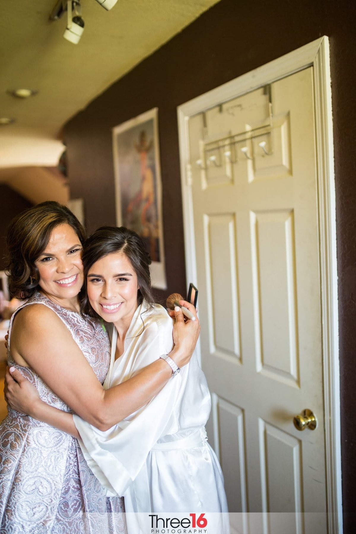 Bride gets a hug from her mother while getting ready for her wedding