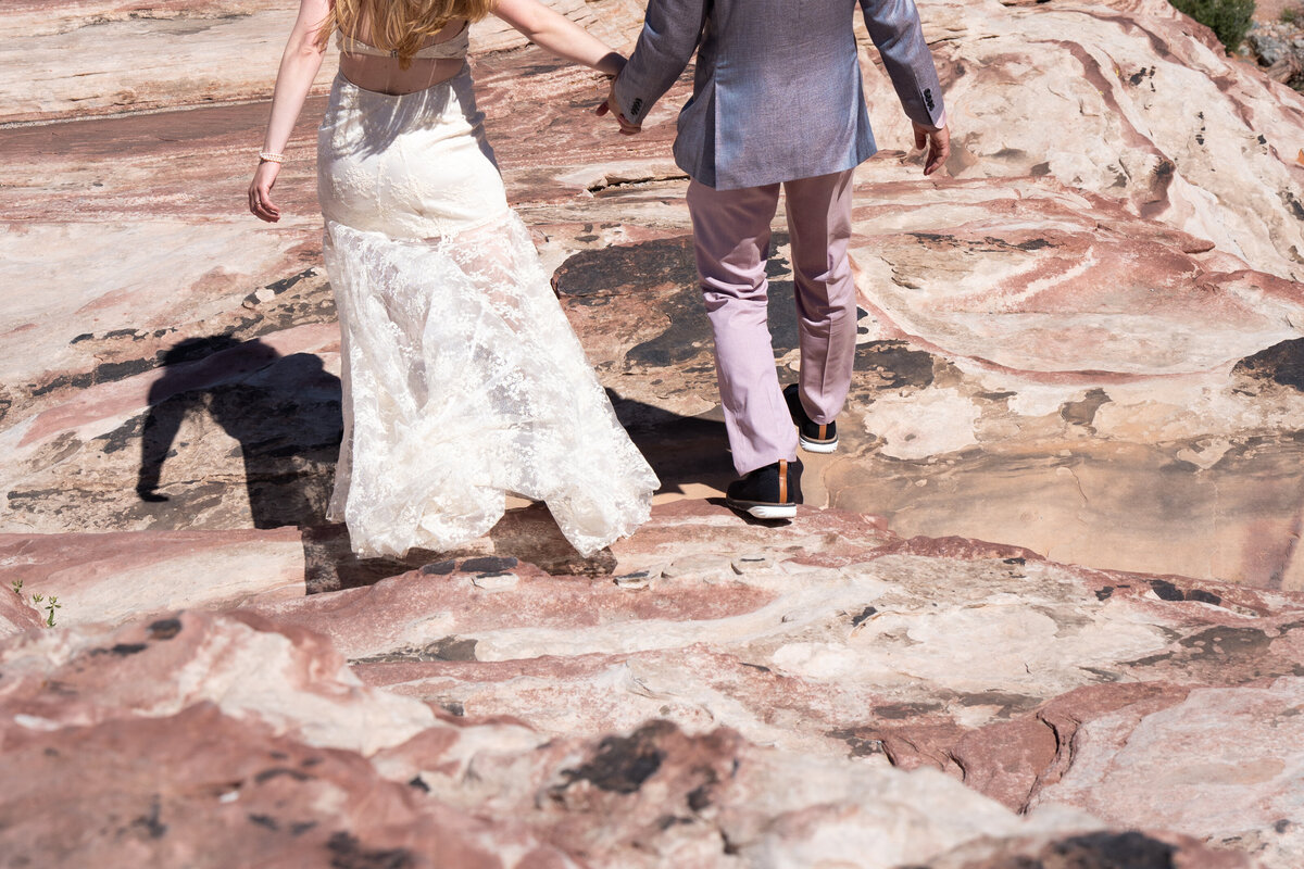 A couple holding hands and walking up a rock