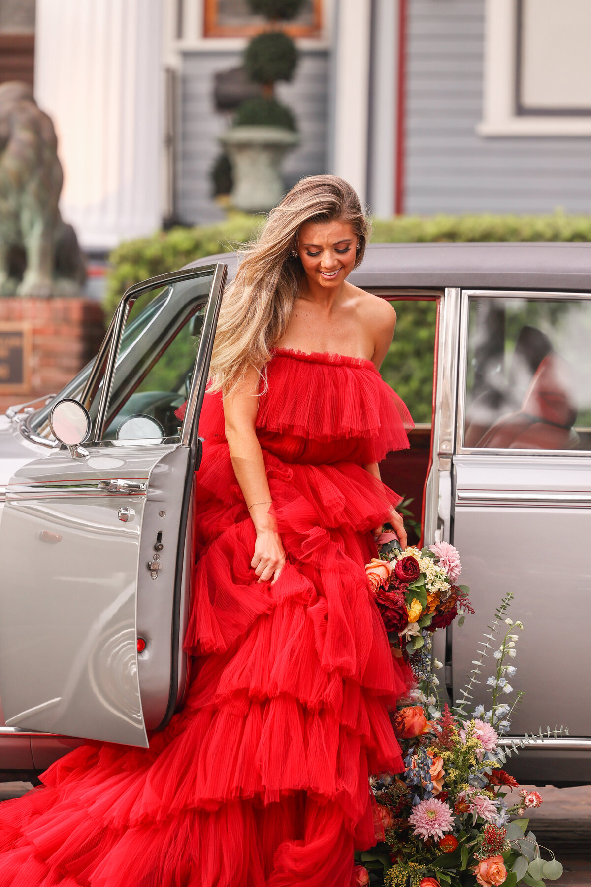 woman in red dress getting out of vintage car with beautiful florals in Orlando Florida by portrait photographer Amanda Richardson Photography