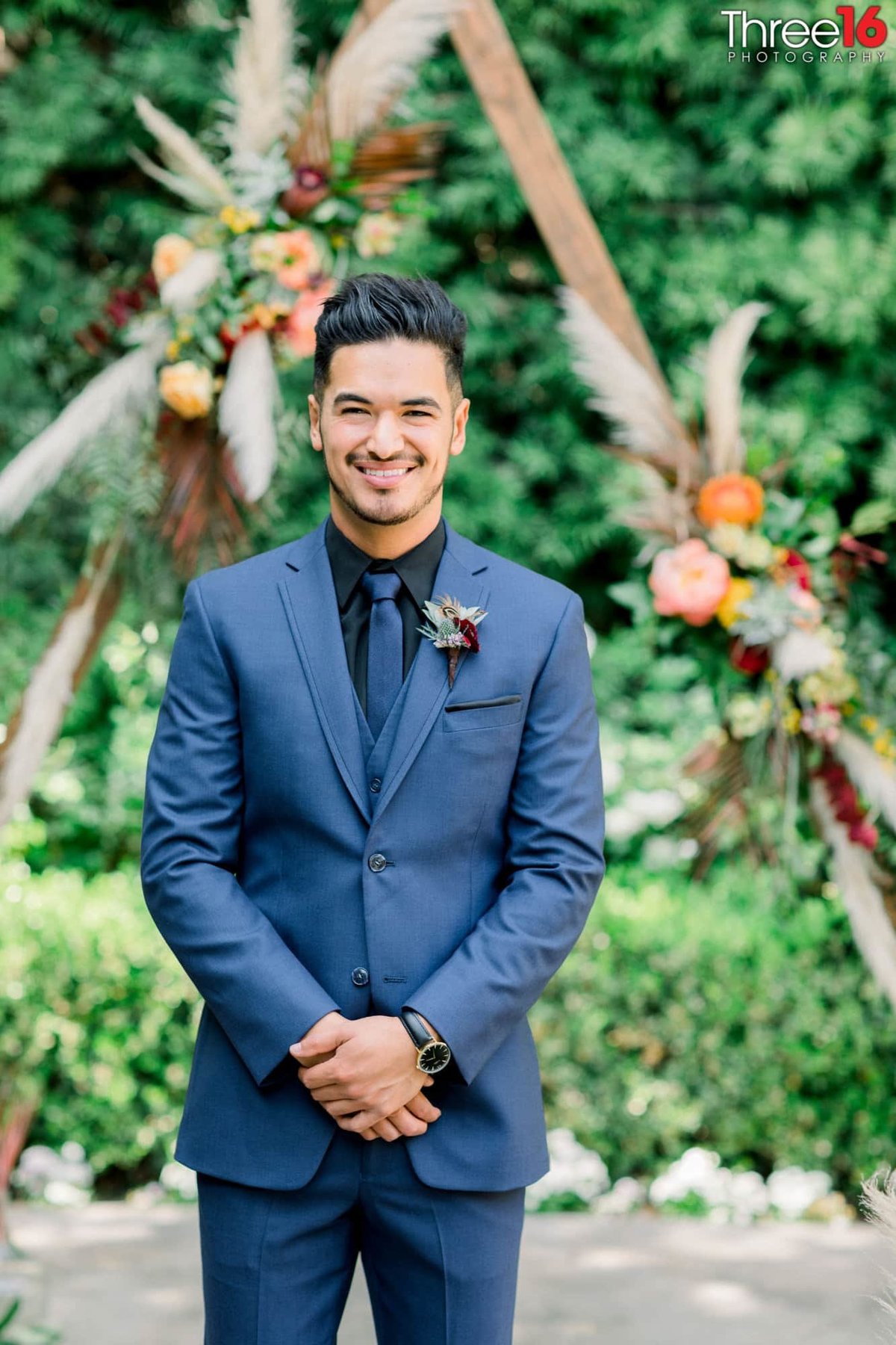Groom smiles as he poses in his blue suit